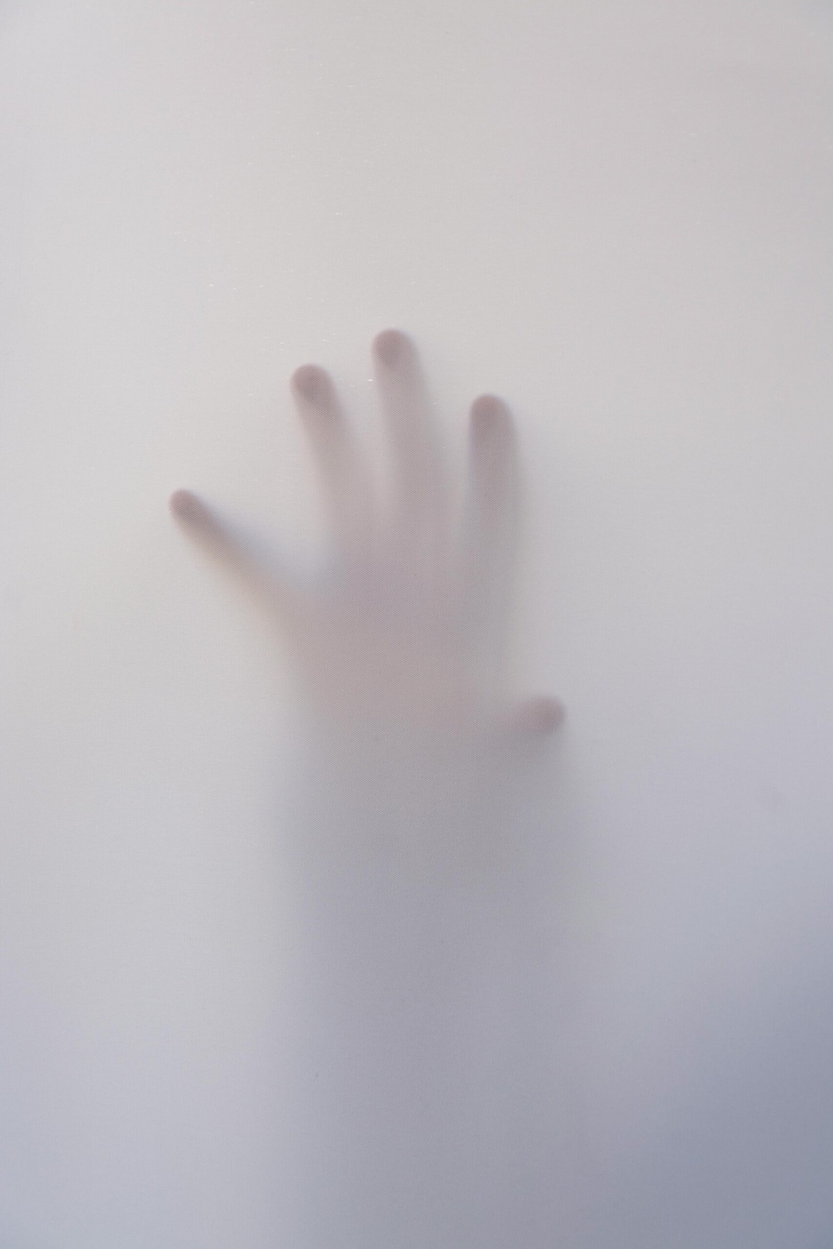 Blurred hand behind frosted surface symbolizing nervous system overwhelm and the need for a calming reset