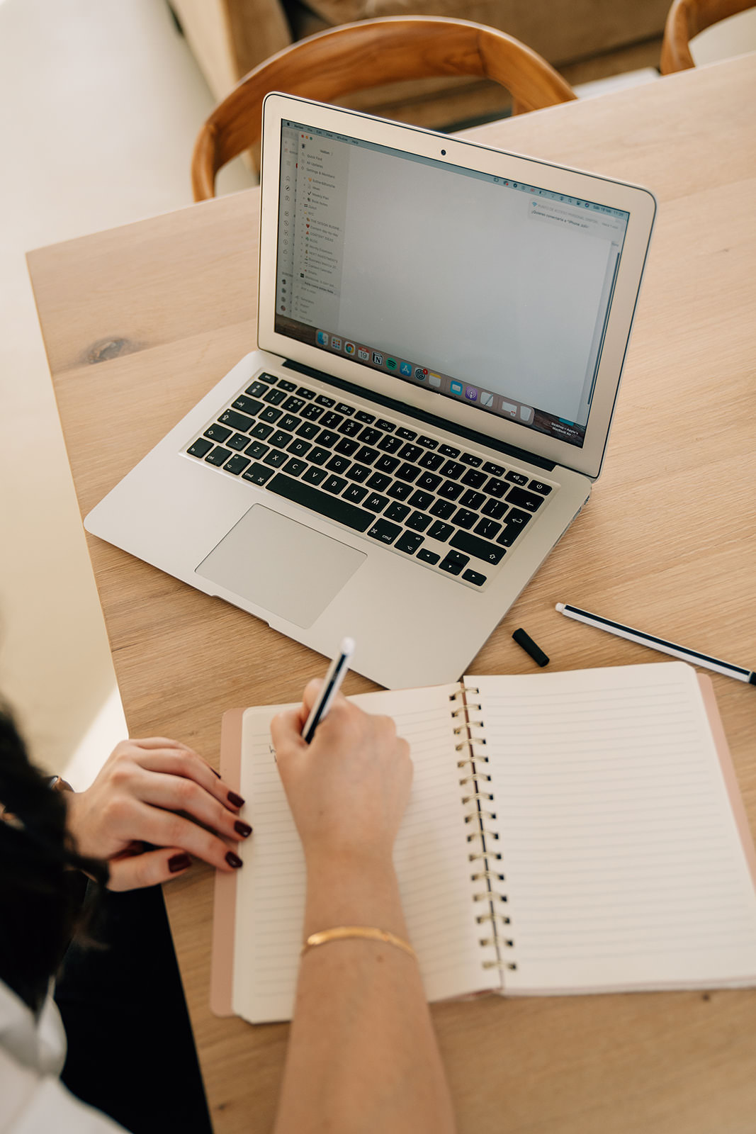 Woman journaling beside a laptop during an afternoon work session, supporting focus, clarity, and a calm midlife reset routine.